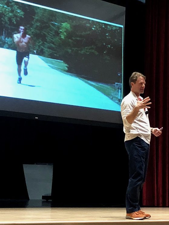 Chris Korfist presenting sprint mechanics video analysis on stage at a coaching clinic